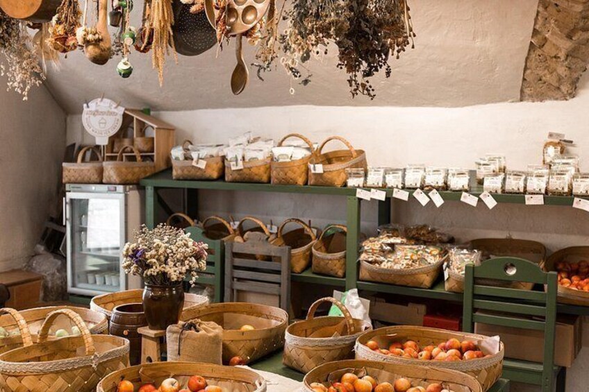 A market stall with baskets of fruits, wooden containers, and hanging dried herbs. 3