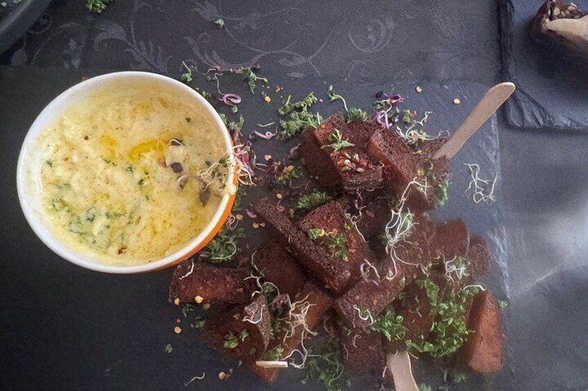 A bowl of soup with a spoon, and a plate with food garnished with herbs and sprouts. 4