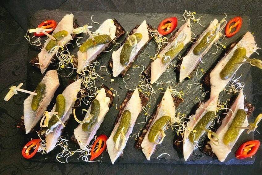 A platter of fish fillets on toast with pickles and sprouts. 3
