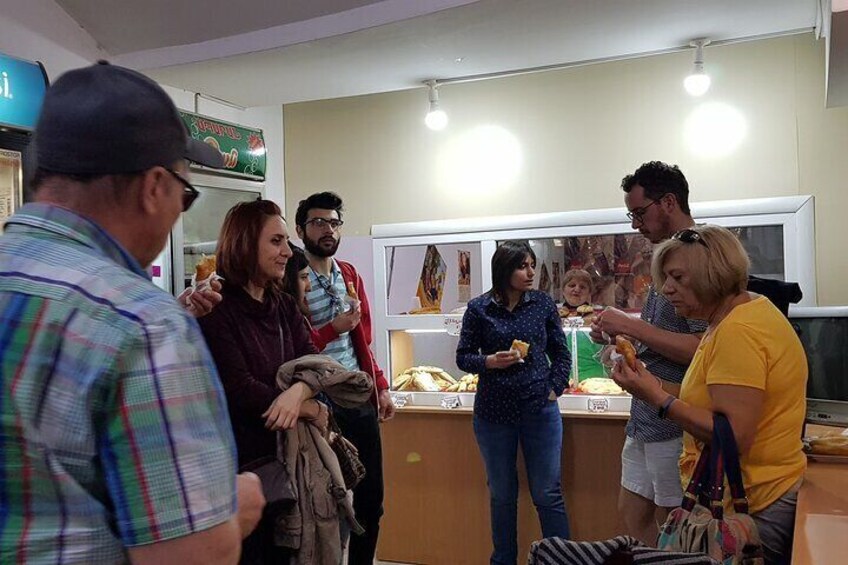 A group of people in a food court, some eating and others conversing. 5