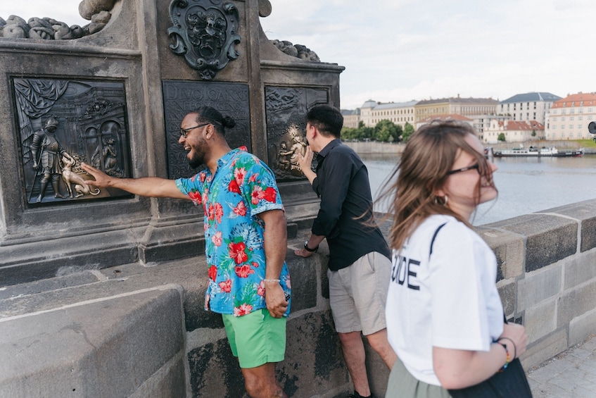 Een groep mensen staat bij een historisch monument met inscripties en reliëfbeeldhouwwerken. 4