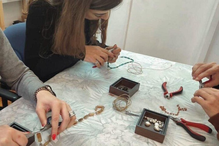 Une personne travaille sur un projet de loisirs créatifs, utilisant des perles et des outils, sur une table. 5