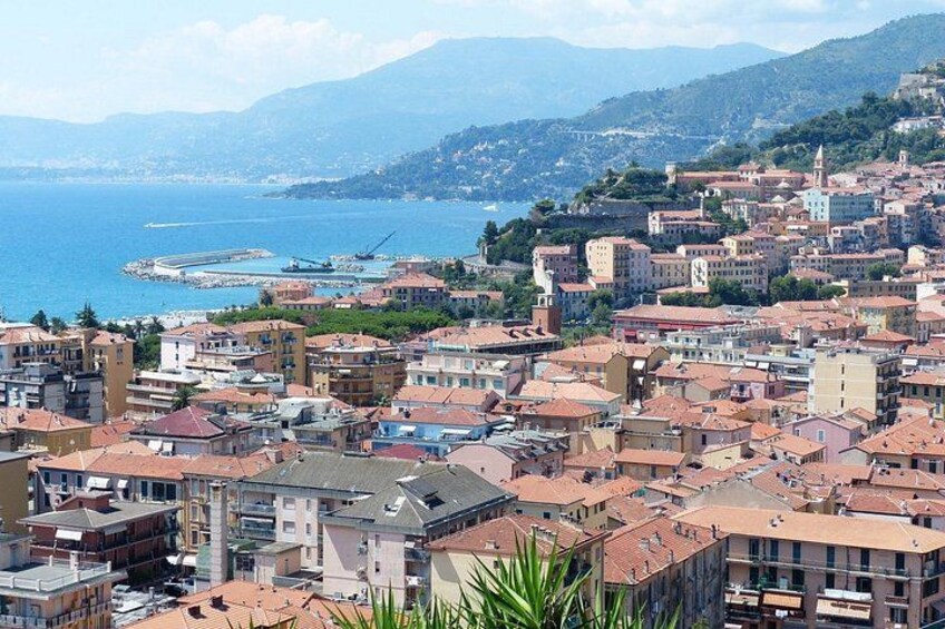 A coastal cityscape with buildings, a harbor, and mountains in the background. 4
