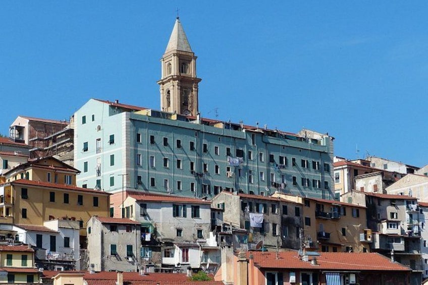 A historic town with a prominent church tower, colorful buildings, and a clear blue sky. 2