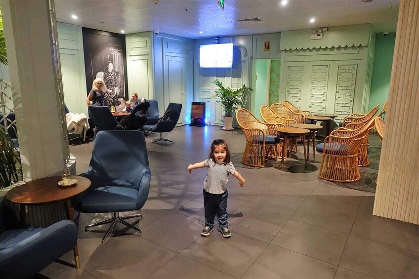 A child walking in a cafe with blue chairs and wicker tables. 2