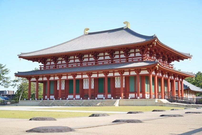 Un edificio japonés tradicional con techo curvo, columnas rojas y ventanas verdes. 4