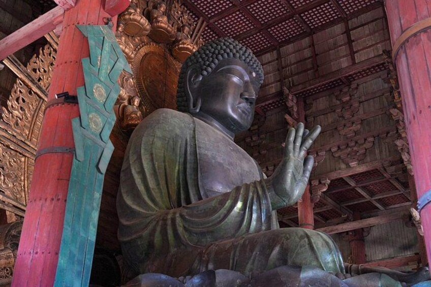 En stor siddende Buddha-statue i et tempel med detaljerede træudskæringer og en traditionel tagkonstruktion. 3