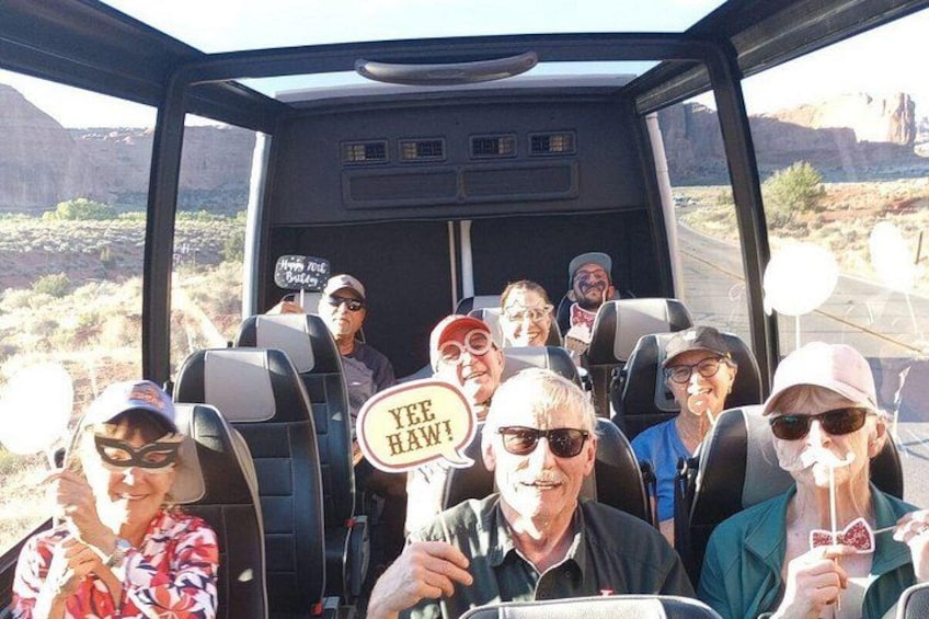 A group of people in a vehicle with a desert landscape in the background. 3