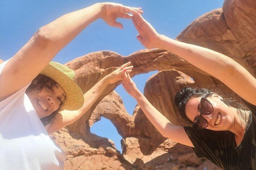 Two people making a heart shape with their hands against a rocky landscape. 4