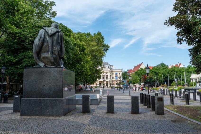 Una estatua en una plaza pública con árboles y edificios al fondo. 3