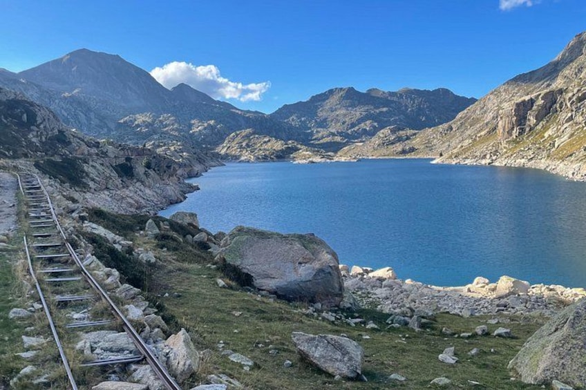 A mountainous landscape with a railway track, a lake, and rocky terrain. 3