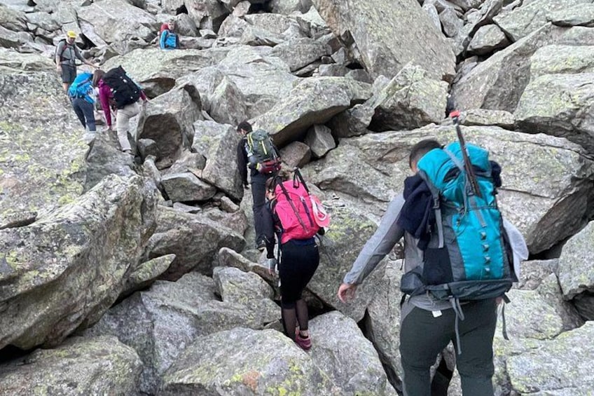 Hikers navigating a rocky terrain with large boulders. 4