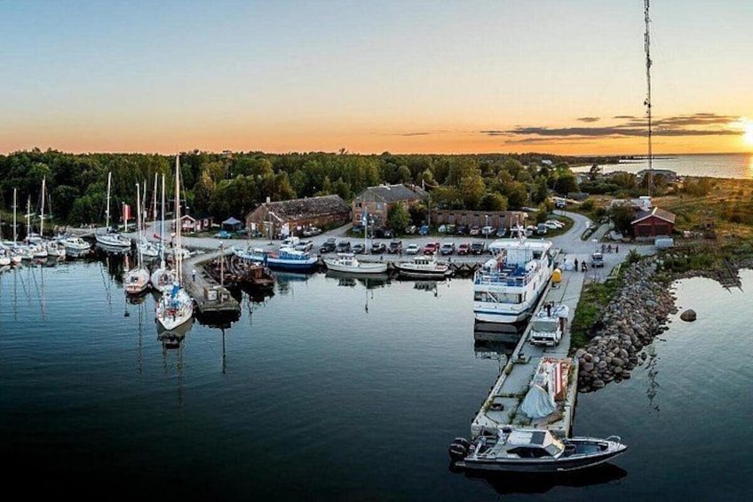 Een jachthaven met aangemeerde boten, een steiger en een ondergaande zon op de achtergrond. 1