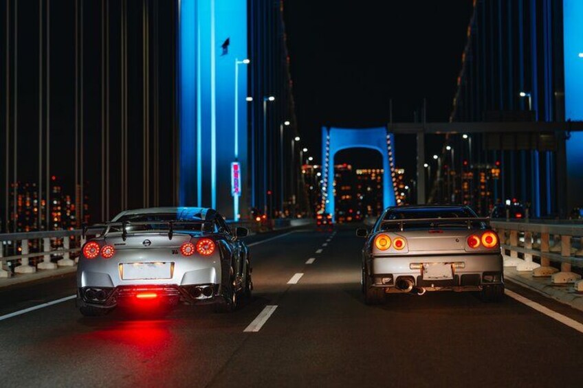 Due auto sportive su un ponte illuminate con luci blu, di notte. 3