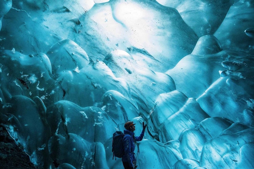 A person hiking in a glacier with ice formations. 2