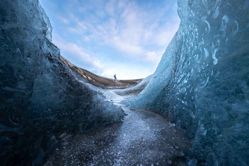 A narrow ice cave with a person standing at the far end. 3