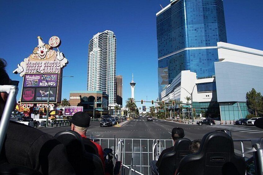 A city street with a tall building, a casino sign, and a clear blue sky. 3