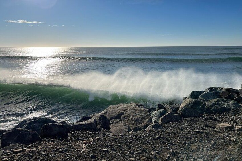 A rocky shoreline with waves crashing against the rocks under a clear sky. 5
