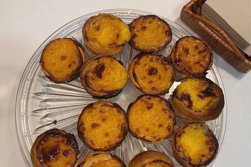 En tallerken med portugisiske cremebrød på en klar glasskål. 1