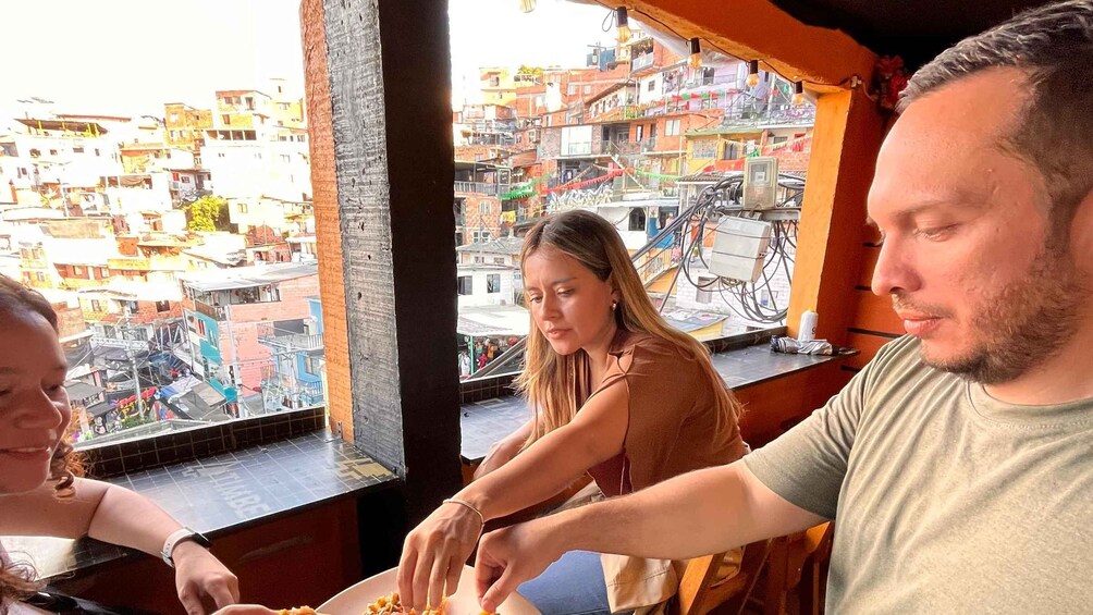 A group of people preparing food at a table with a view of a densely packed urban area. 2