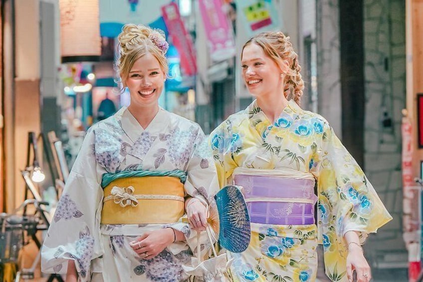 Twee personen in traditionele Japanse kimono's lopen over een smalle straat. 3