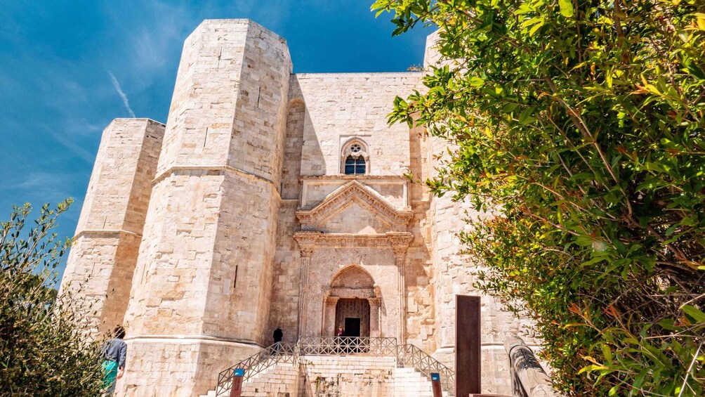 A historic stone building with a central arched entrance, flanked by two tall towers. 1
