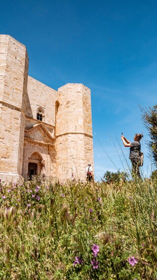 A historic stone building with arched windows and a person pointing towards it. 5
