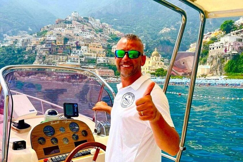 A boat with a man giving a thumbs-up, a scenic coastal village in the background, and a clear blue sea. 3