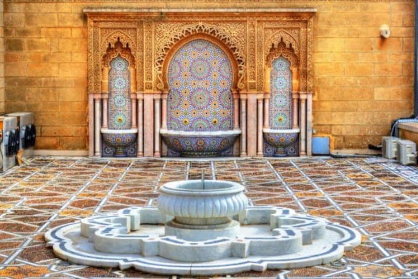 Une cour avec une fontaine, des arches décorées et des carreaux aux motifs variés. 3