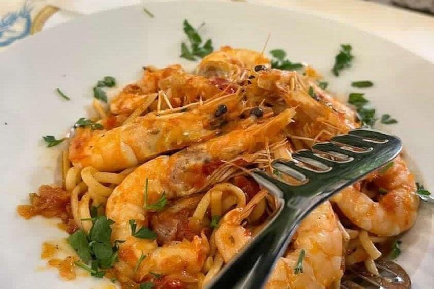 A plate of pasta with shrimp, garnished with herbs. 2