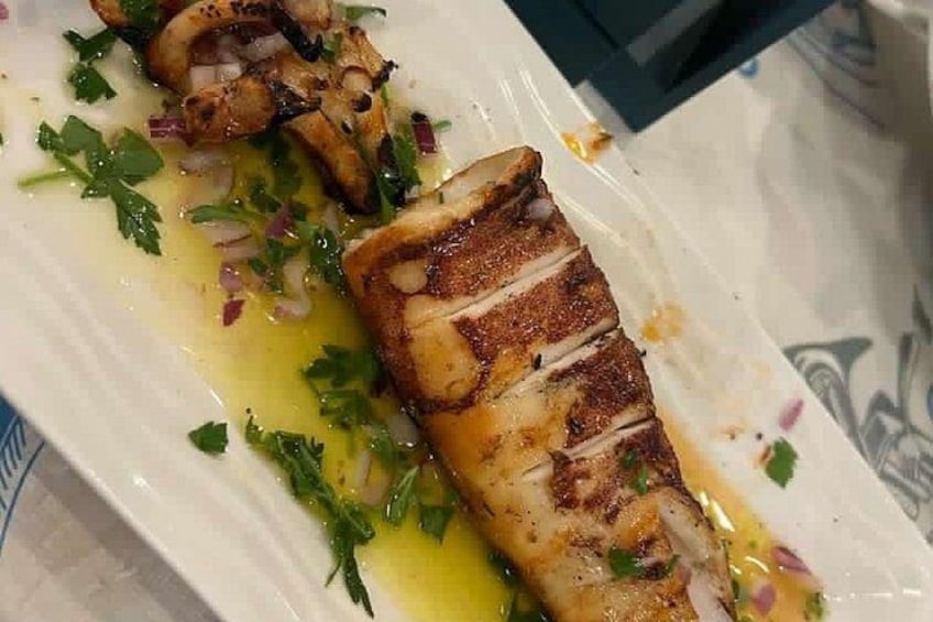 Un plato de pescado a la parrilla, adornado con hierbas y cebollas. 2