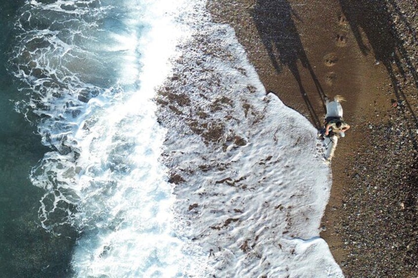 Una persona caminando sobre una playa rocosa, con olas rompiendo en la orilla. 4