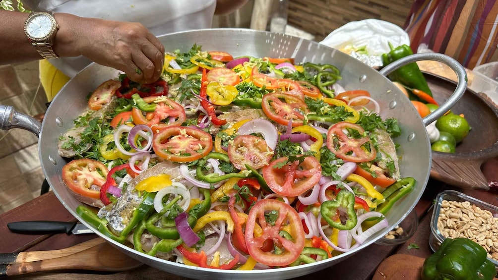 A person preparing a colorful vegetable dish in a large pan. 5