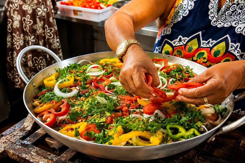 A person preparing a colorful vegetable dish in a large pan. 1