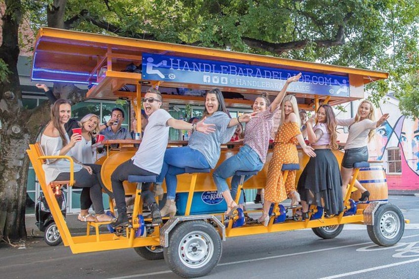Een groep mensen in een gele kar met een bord waarop staat 'HANDLEBARADALE.COM'. 1
