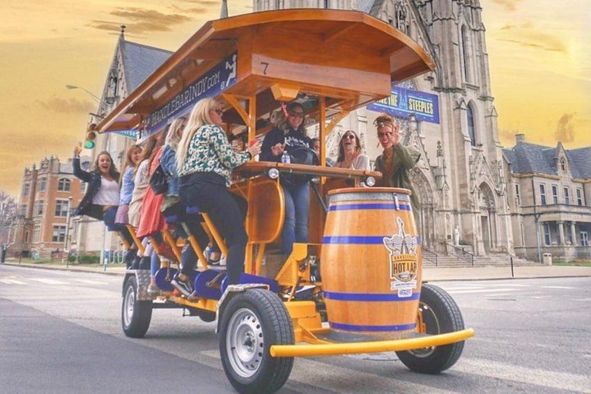 Un groupe de personnes se trouve dans un tramway d’époque, devant lequel est placé un baril sur lequel on peut lire « HOT TAILS », le tout se déroulant devant un bâtiment historique. 5