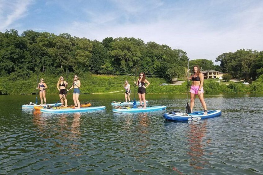Personas haciendo paddleboard en un lago tranquilo, con árboles y una casa al fondo. 4
