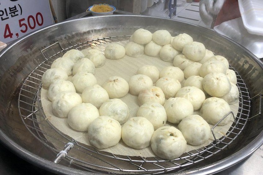 A large metal pan with a wire rack containing round dumplings. 2