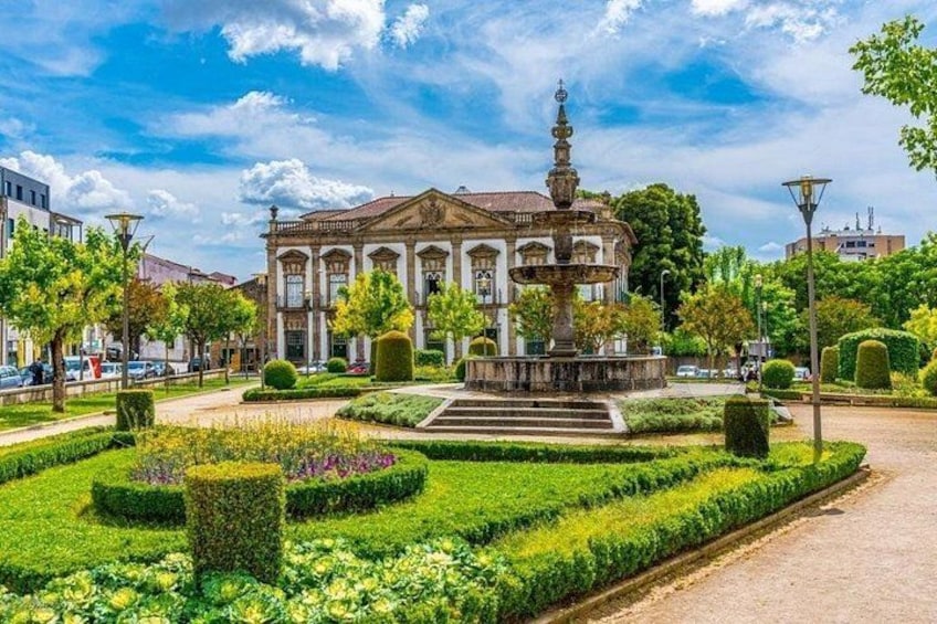 A historic building with a fountain, surrounded by well-manicured gardens and a clear blue sky. 2