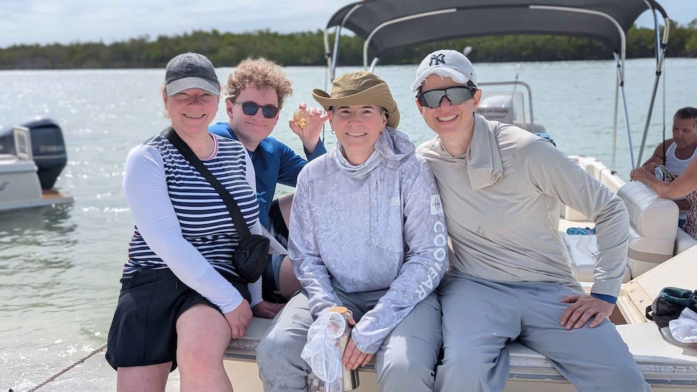 Un grupo de personas en un bote con agua y árboles al fondo. 1