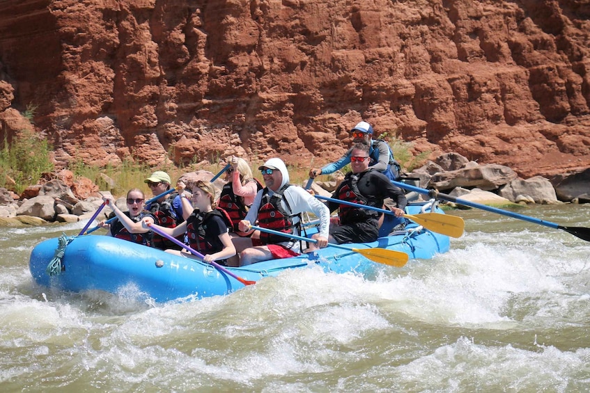 A group of people rafting on a river with red rock formations in the background. 4