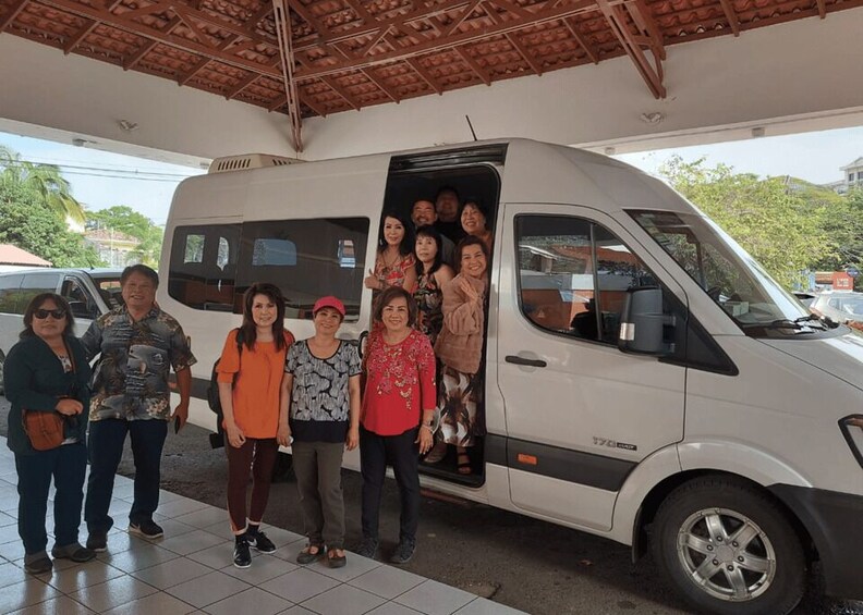 A group of people standing in front of a white van with its door open. 1