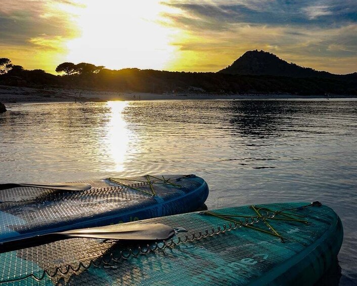 A pair of inflatable shoes on a boat, a calm river, and a mountain in the background during sunset. 2