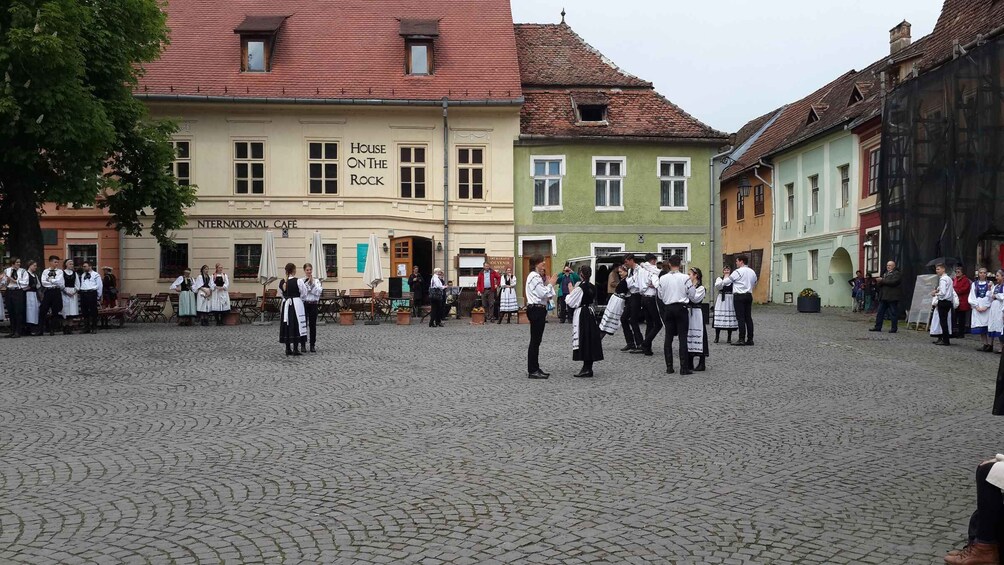 A cobblestone square with people in traditional attire, a building labeled "House on the Rock", and an "International Cafe". 5