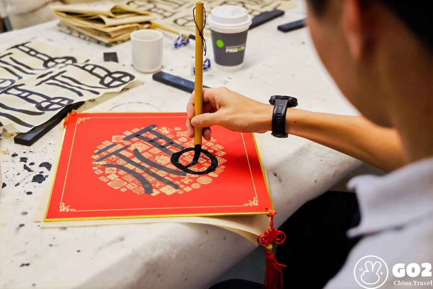 A person writing Chinese calligraphy on a red book with gold borders. 4