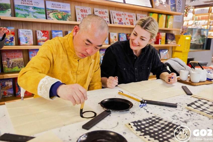Two people engaged in a traditional tea ceremony, with tea utensils and books on a table. 3