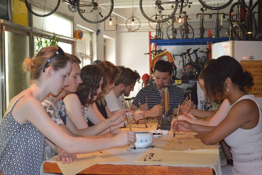 A group of people playing a board game at a table in a room with bicycles hanging from the ceiling. 1