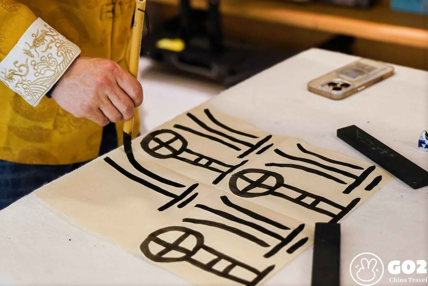 A person drawing on a large sheet of paper with black ink, using a brush. 5