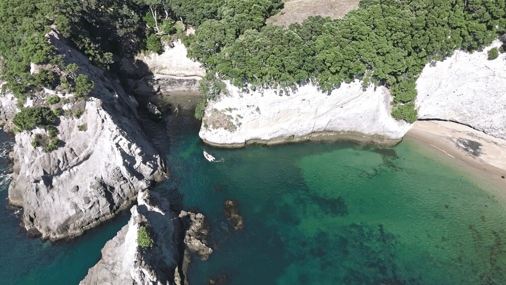 A coastal landscape with rocky cliffs, clear turquoise waters, and a sandy beach. 3