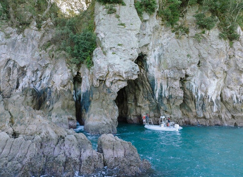 A rocky coastal cave entrance with a boat near the shore. 1